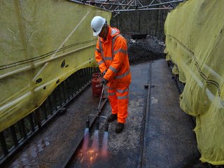 A trident gas torch was used to dry the surface of hte concrete deck. What appear to be rails in the concrete surface are actually the ironwork of the bridge structure, the sections being bolted together